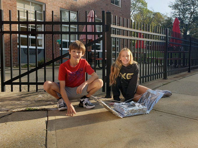 Two students pose outside with the solar oven they built.