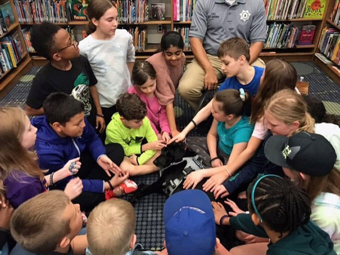 Students gather around and pet Pawfficer Sage.